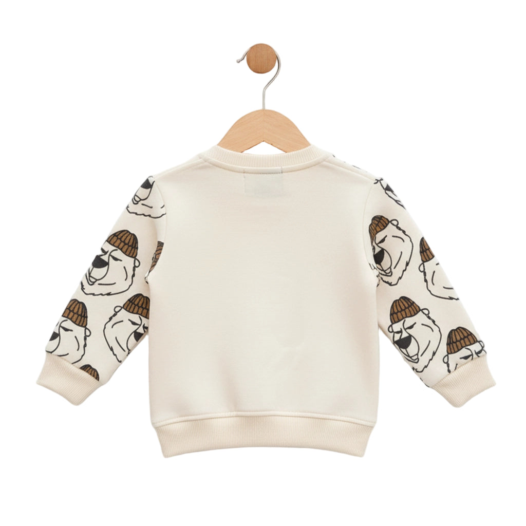 Children's sweater with bear prints on sleeves, hanging on a wooden hook against a white background