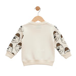 Children's sweater with bear prints on sleeves, hanging on a wooden hook against a white background