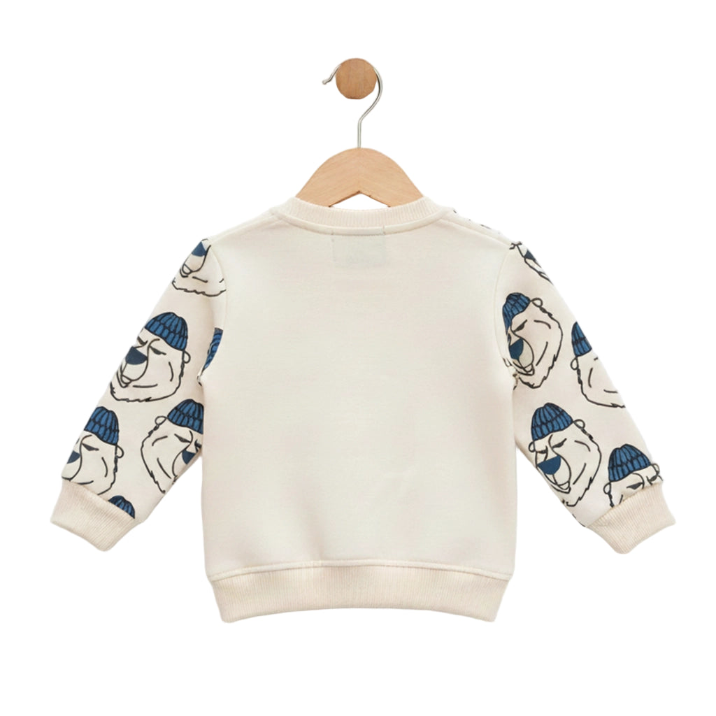 Children's sweater with bear pattern on sleeves hanging on a wooden hanger against a white background