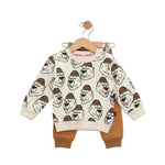 Children's outfit with patterned top and brown pants on a hanger against a white background