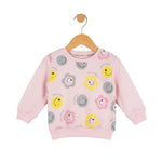 Pink children's sweatshirt with smiley face patterns on a hanger against a white background