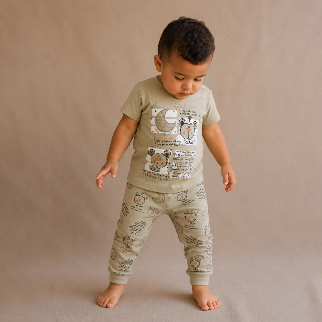 Child wearing a green t-shirt and matching pants with animal prints on a beige background