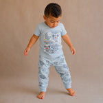 Child wearing a light blue pajama set with teddy bear designs on a beige background