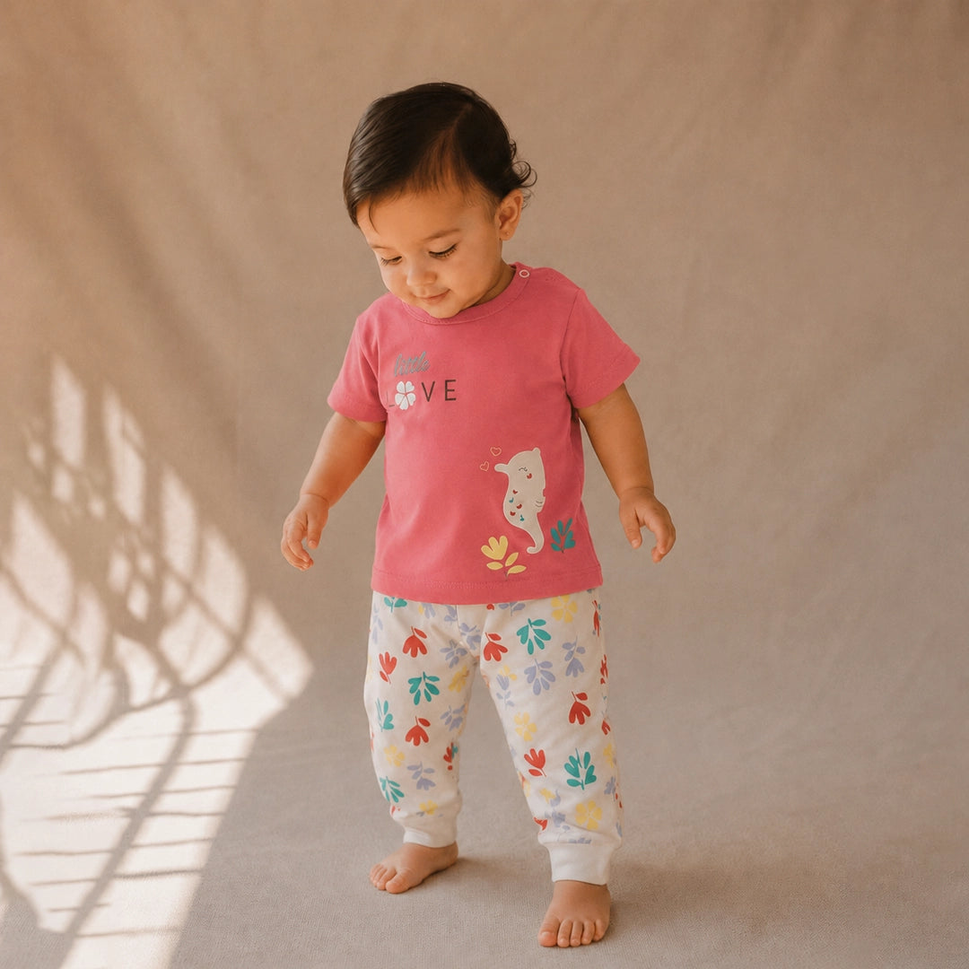 Child wearing a red shirt and colorful pants standing against a beige background