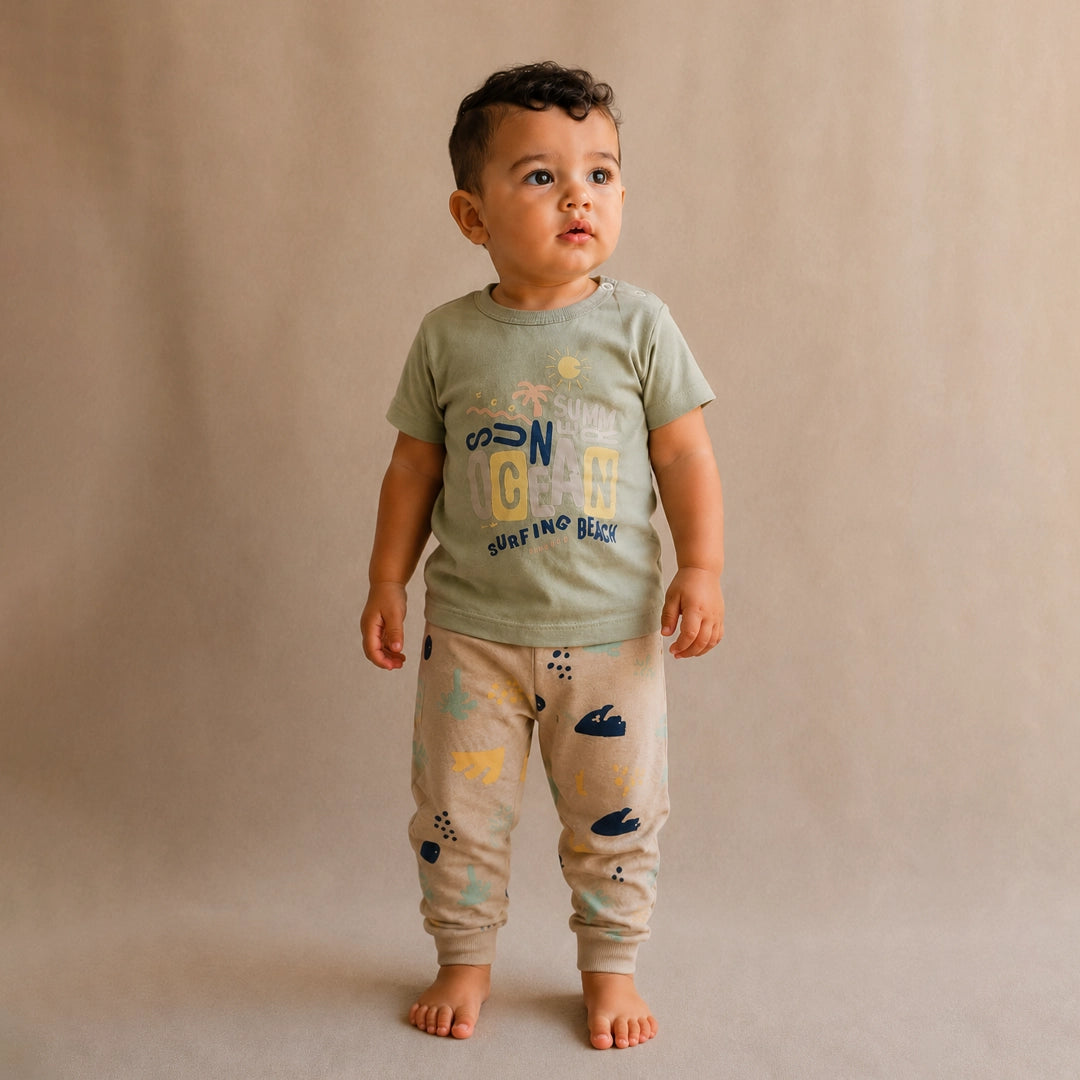 Child wearing a green t-shirt and beige pants with a pattern on a beige background