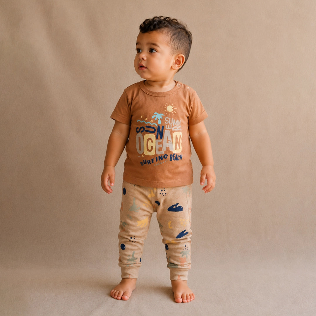 Child wearing a brown t-shirt and patterned pants on a beige background