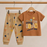 Children's brown shirt and pants set with beach-themed design on a beige background