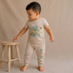 Child wearing a beige outfit with animal prints on a beige background