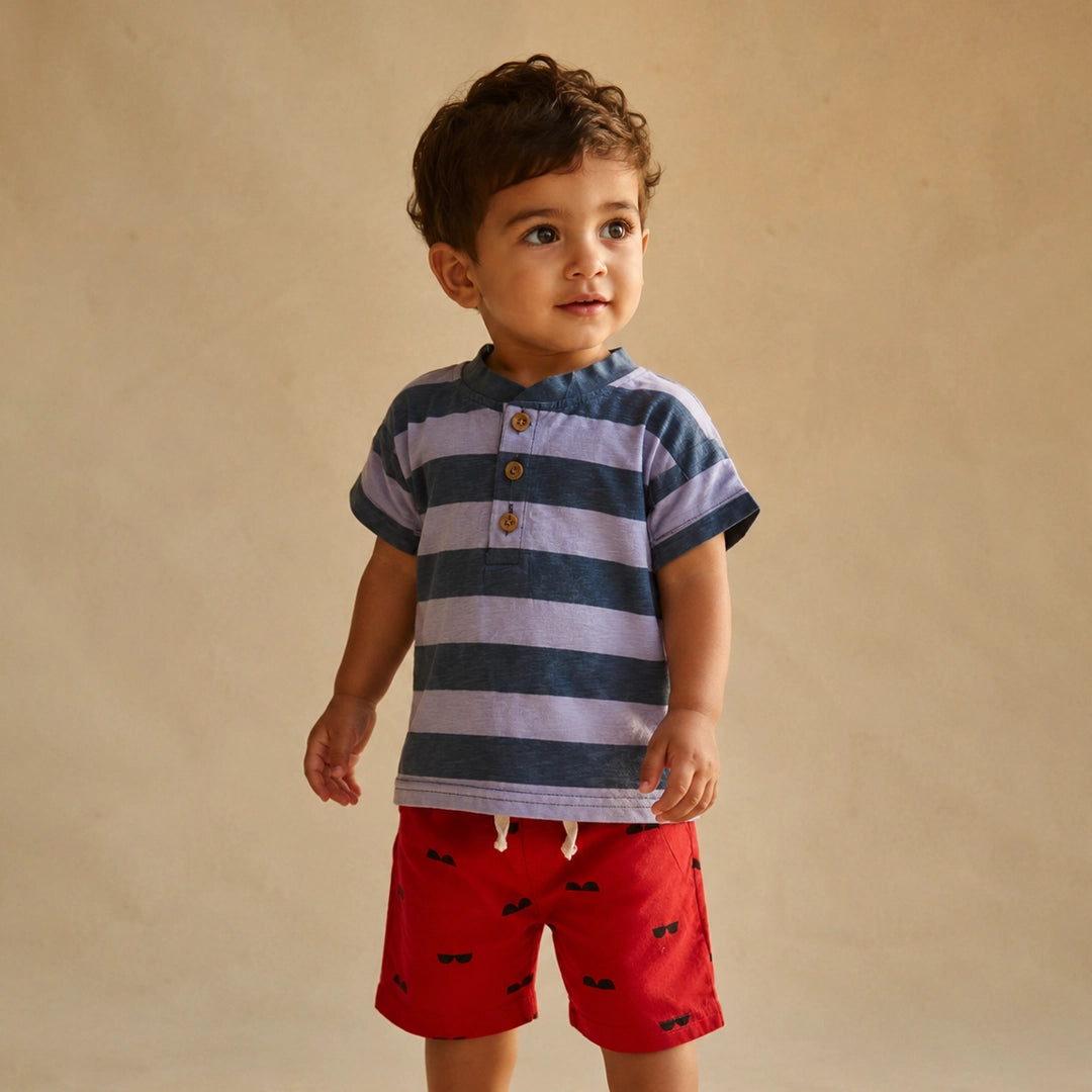Child wearing a striped shirt and red shorts against a beige background