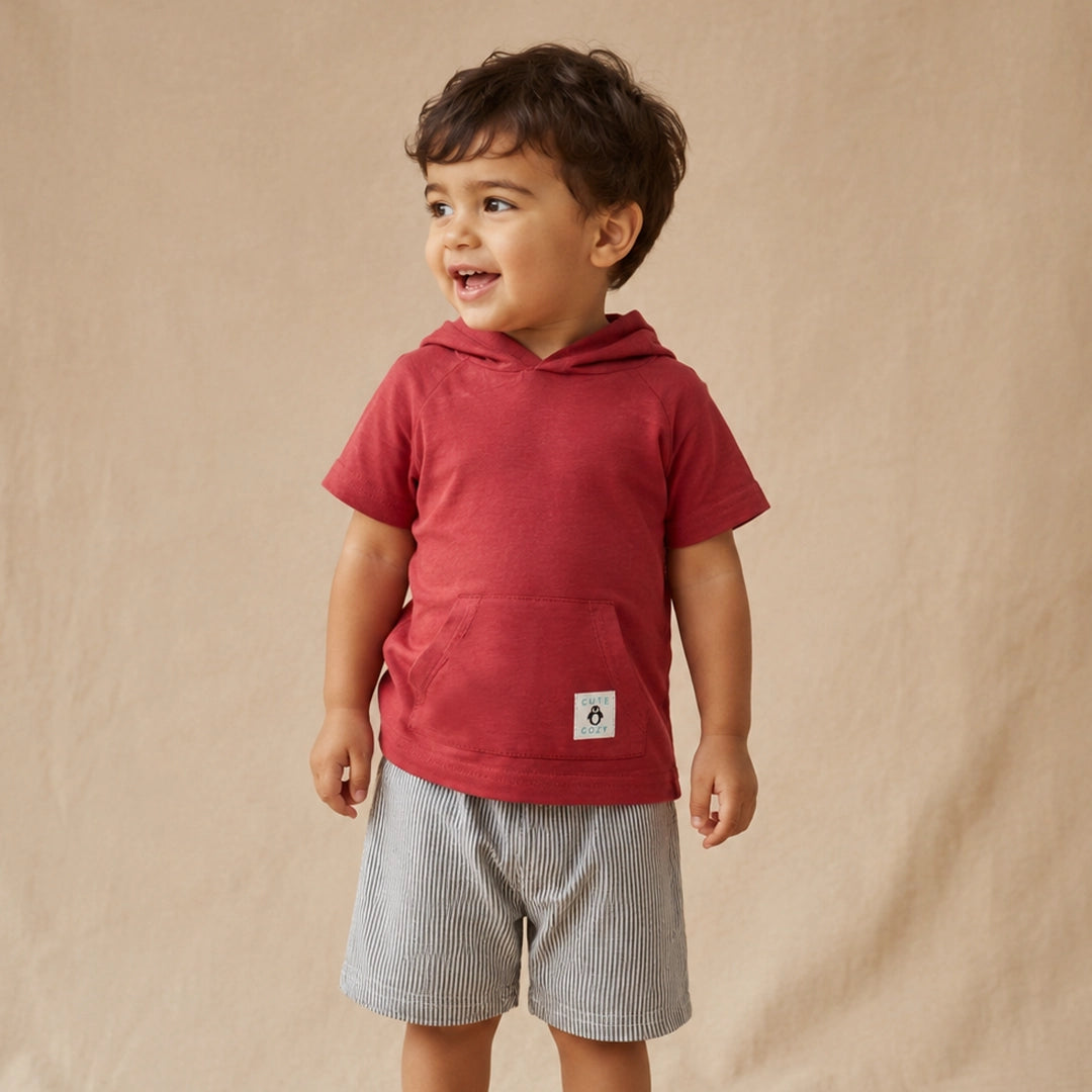 Child wearing a red hoodie and gray shorts on a beige background