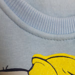 Close-up of a light blue fabric with a yellow character design.