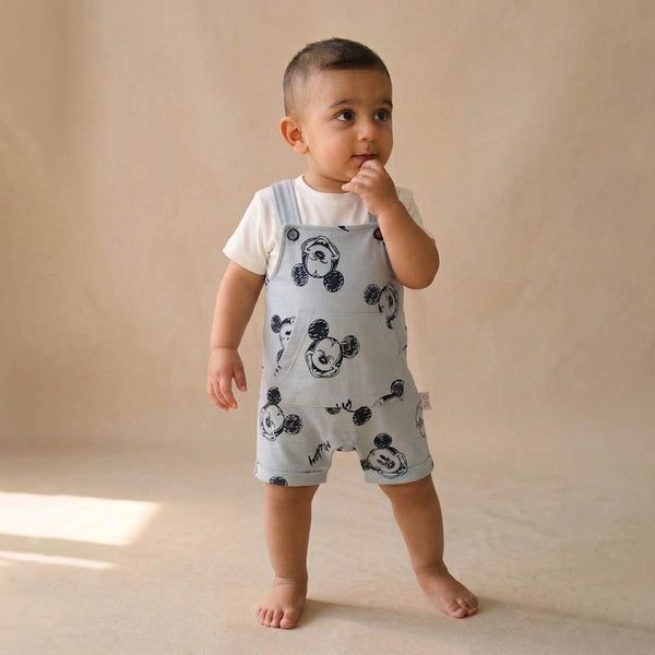 Child wearing a light blue romper with black patterns on a beige background