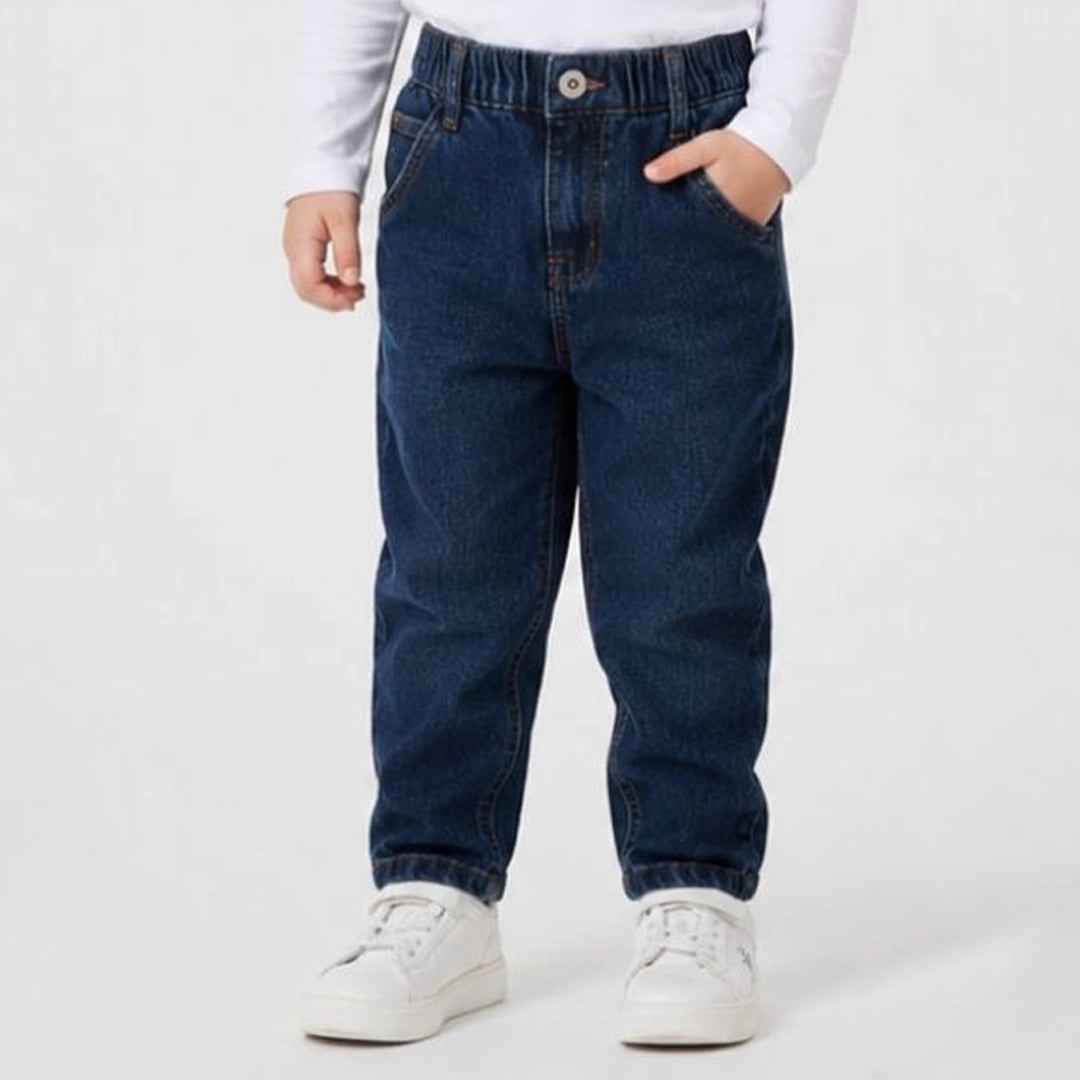 Toddler wearing blue jeans and white sneakers on a plain background