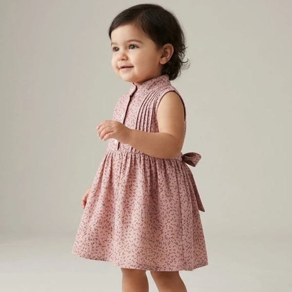 Child wearing a pink floral dress on a plain background