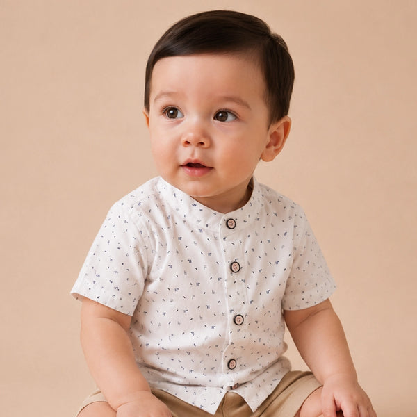 Baby wearing a white shirt with black patterns on a plain background