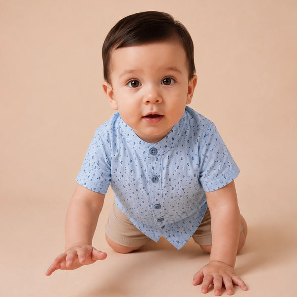 Child wearing a light blue shirt with small patterns and dark jeans on a plain background