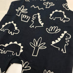 Black baby romper with white dinosaur patterns on a beige background