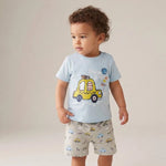 Child wearing a light blue t-shirt with a yellow car design and patterned shorts on a plain background
