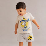 Child wearing a t-shirt and shorts with a cartoon character design on a plain background