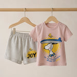 Pink t-shirt with cartoon character and gray shorts with 'JOY' text on a beige background