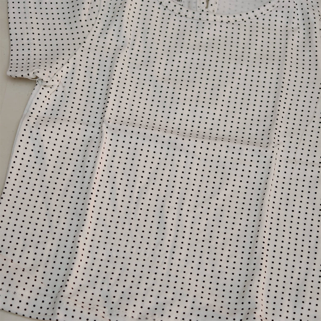 Close-up of a white shirt with black dot pattern on a light gray background