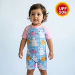 Child wearing a colorful swimsuit with cartoon designs on a light blue background, featuring a UPF 50+ label.