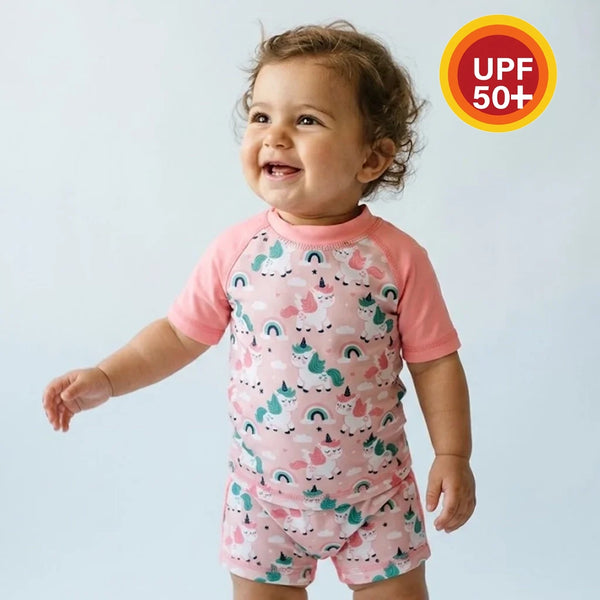 Child wearing a pink and unicorn patterned outfit with a UPF 50+ label on a light blue background