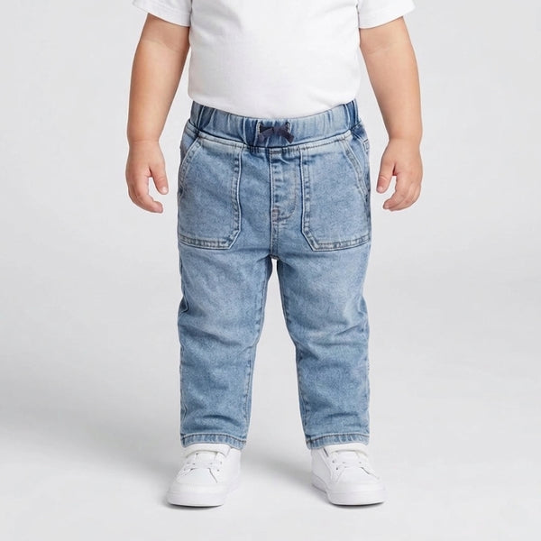 Child wearing light blue jeans and white shoes on a plain background